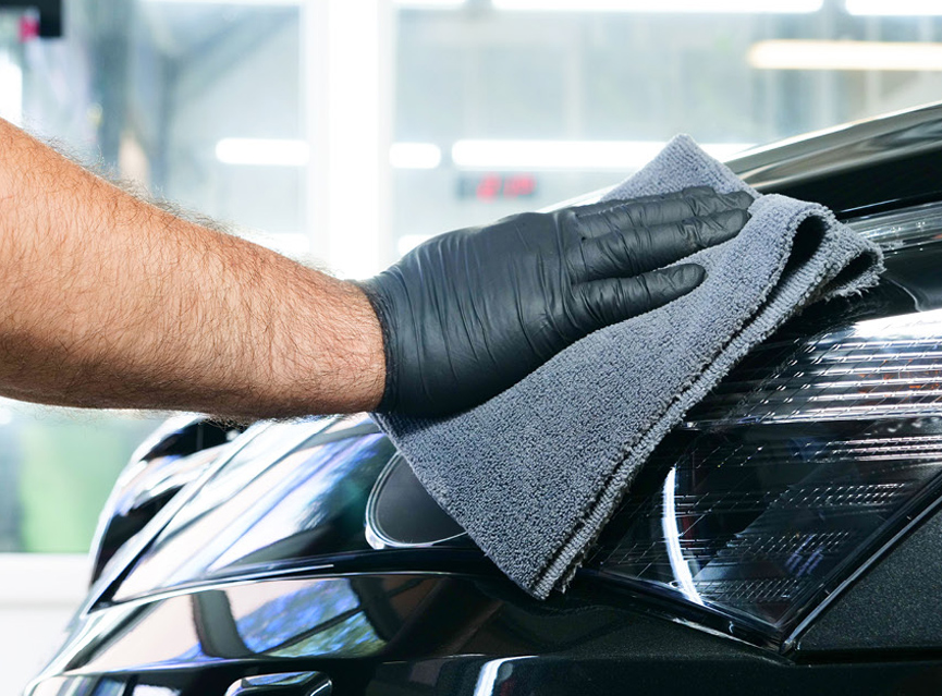 Person cleaning vehicle headlight